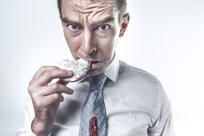 man eating doughnut looking worried