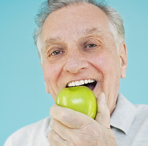 senior man eating a green apple