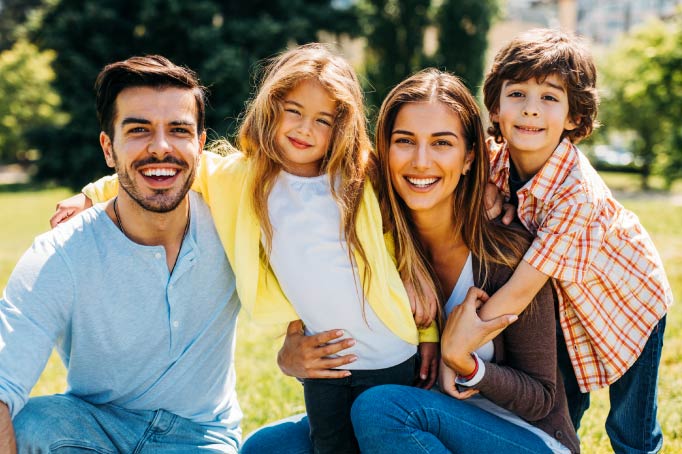 dad with facial hair, young daughter, mom with long brunette hair, and young son outside