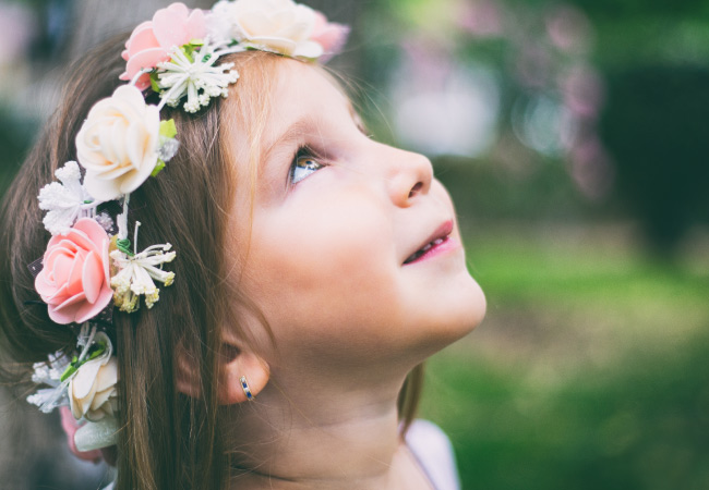 Side closeup of a brunette girl wearing a floral crown looking up to the sky