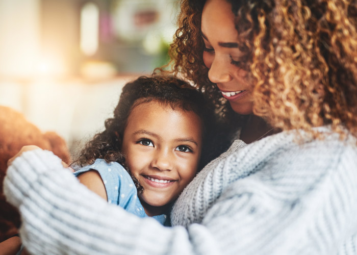 Curly-haired mother embraces her little daughter as they both smile and talk about mouthwash