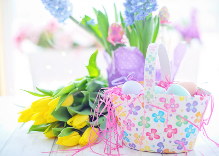 Easter basket of Easter eggs next to a bouquet of yellow tulips