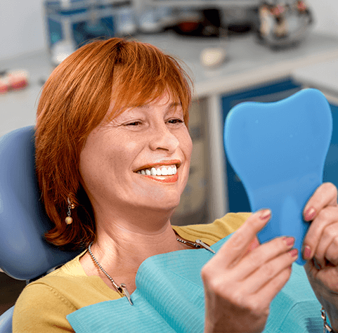 woman in dental chair smiling at mirror