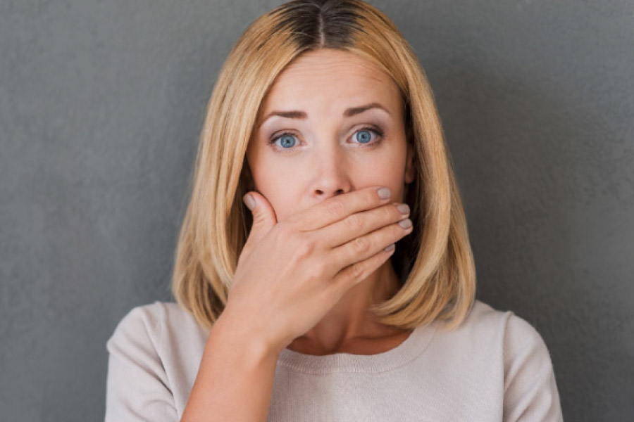 woman covers her mouth with her hand to hide gum disease