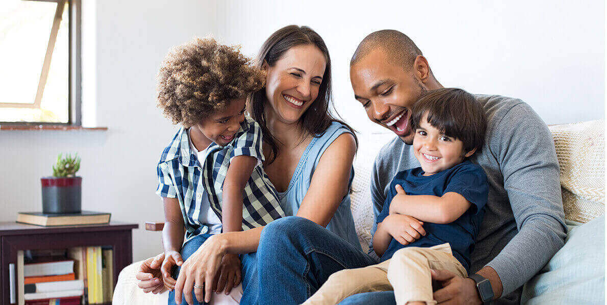 Mixed family laughing on a couch together