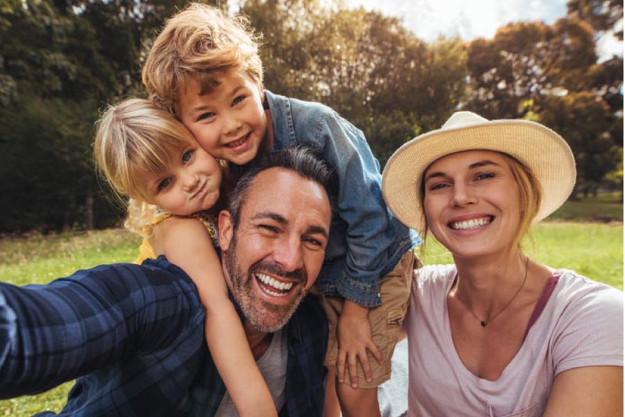 young family of four hug and smile after learning the benefits of a family dentist