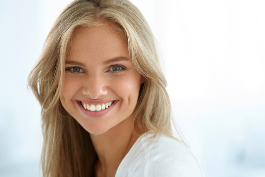 young woman flashes a white bright smile after cosmetic dentistry treatments