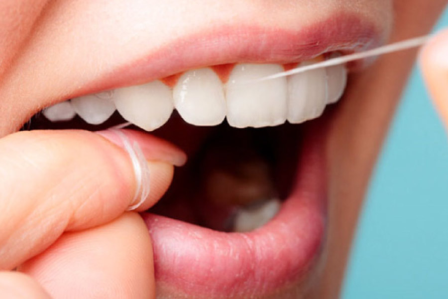 close up of a woman's mouth as she flosses her teeth