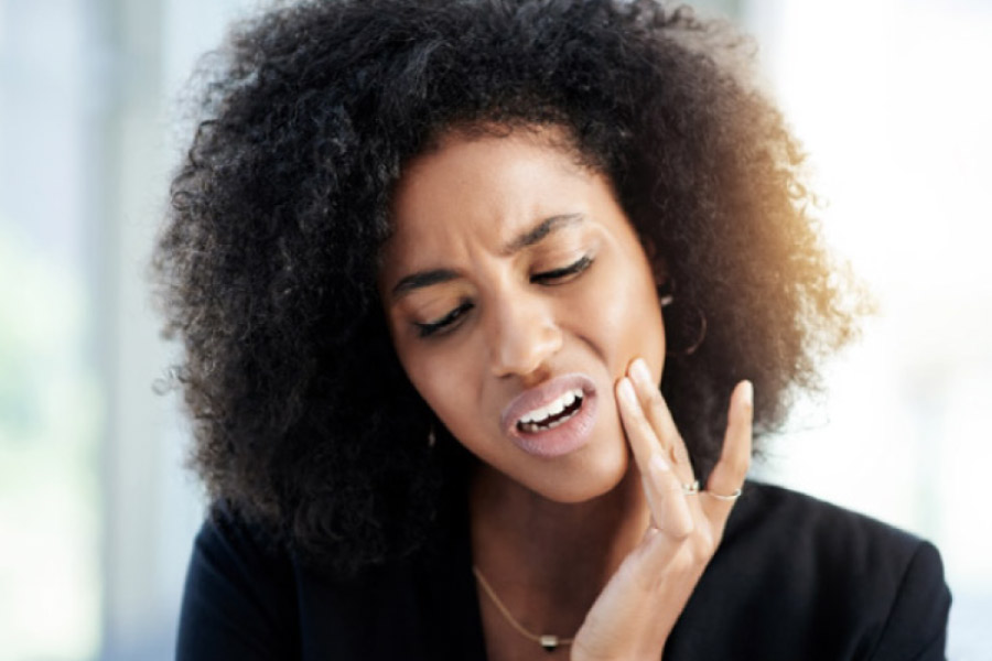 young woman holds her jaw in pain from a dental emergency