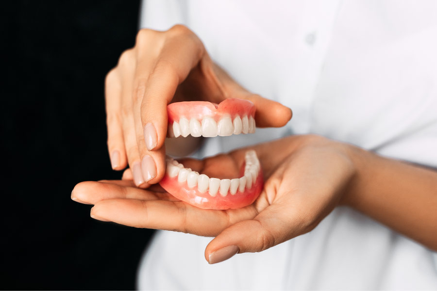 pair of hands holding a set of dentures