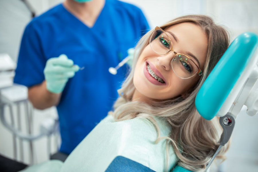 young woman gets her braces adusted by the orthodontist