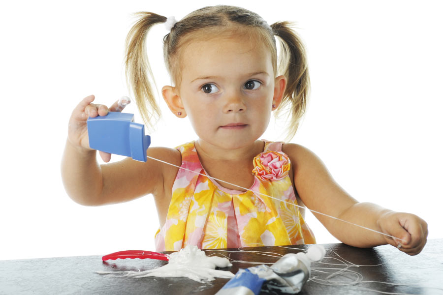 young girl with pigtails pulls out a long strand of dental floss